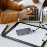 A man transfers files from a laptop to a disk.