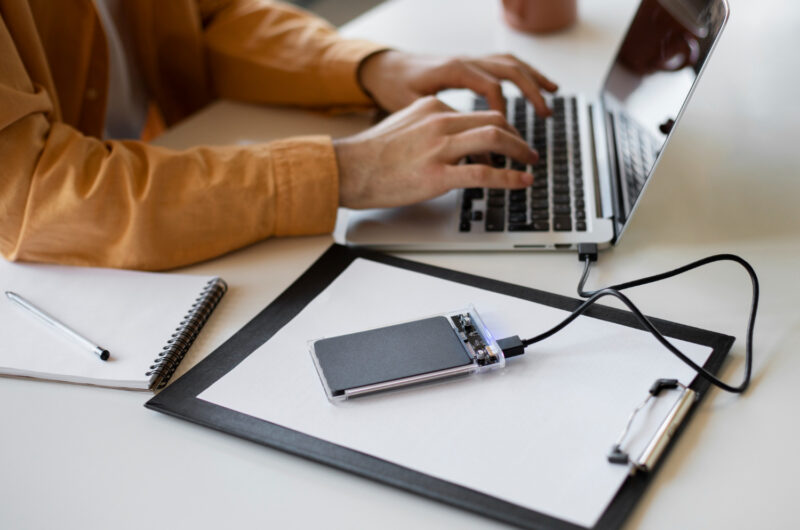 A man transfers files from a laptop to a disk.