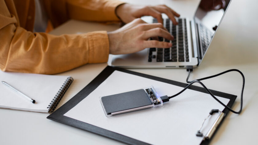 A man transfers files from a laptop to a disk.